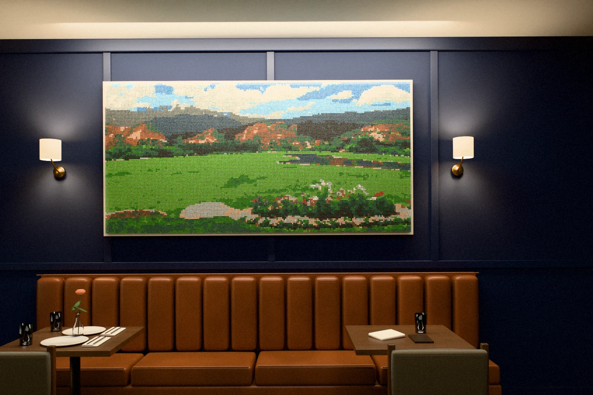 A golf-tee picture of red rock formations, mountains and a green lawn with a flower bed, hung on a navy wall between brass sconces above a leather banquette and two small tables.